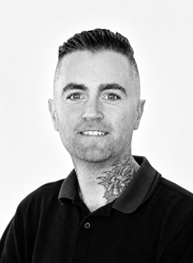 Steven Ramage, in black and white, head and shoulders, wearing a dark polo shirt and looking straight at the camera.